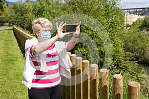 Senior woman taking photo with cellphone at park