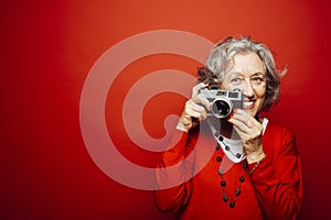 Senior woman taking pictures over a red background