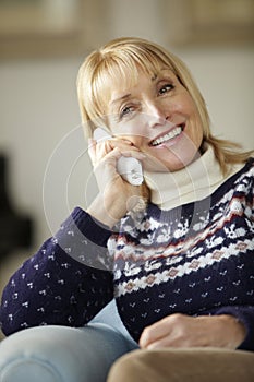 Senior woman talking on cordless phone at home