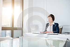 Senior woman talking with headset at the office