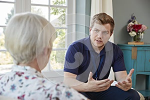Senior woman talking with male care worker on home visit