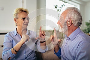 Senior woman talking using sign language with her hearing impairment man