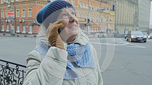 Senior woman talks on phone at the street