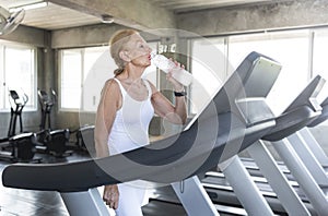 Senior woman thirsty drinking water and exercise jogging at gym fitness. elderly healthy lifestyle