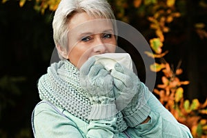 Senior woman with tissue blowing her nose