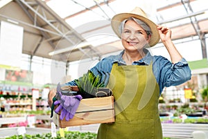 senior woman with tools in box at garden store