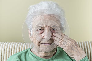 Old woman touching her face, risky for covid-19 contamination