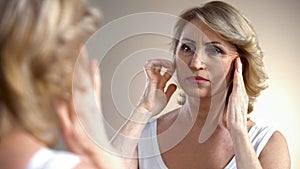 Senior woman touching wrinkled face, thinking about botox injections, age photo