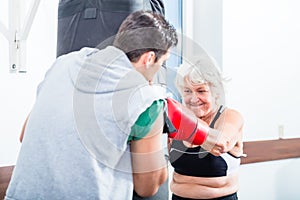 Senior woman with trainer in boxing sparring