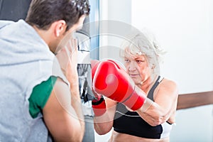 Senior woman with trainer in boxing sparring photo