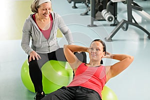 Senior woman with trainer exercising fitness ball