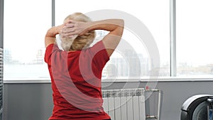 Senior woman training in gym. Back view of retired woman sitting on fitness ball exercising in gym. Concept of active