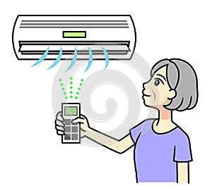 A senior woman turning on an air conditioner with a remote control