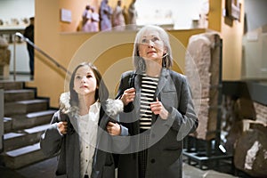 Senior woman and tween girl observing arts and crafts in museum