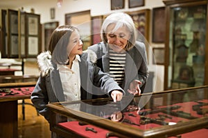 Senior woman and tween girl observing arts and crafts in museum