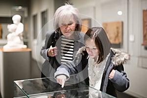 Senior woman and tween girl observing arts and crafts in museum