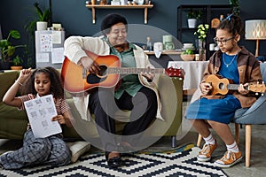 Senior Woman with Two Girls Playing Musical Instruments