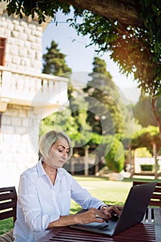 Senior woman typing text on a laptop computer