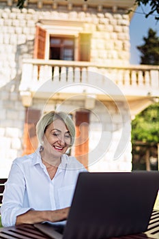 Senior woman typing text on a laptop computer