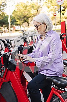 senior woman unlocking rental bike with mobile app