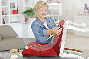 senior woman upholstering chair at home