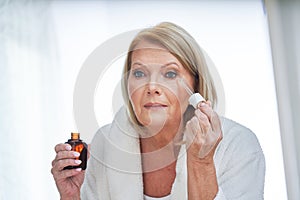 Senior woman using anti wrinkle serum in the bathroom