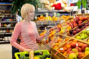 Senior woman using cell phone while shopping at supermarket