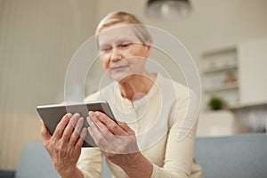 An elderly woman communicates remotely via a tablet with her doctor and takes medications according to his recommendations.