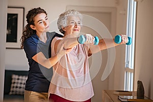 Senior woman using dumbbells with physiotherapist