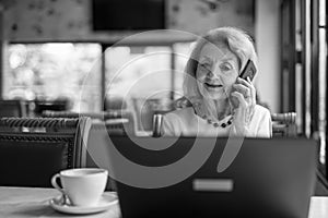 Senior Woman Using Laptop Computer And Mobile Phone