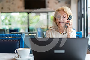 Senior Woman Using Laptop Computer And Mobile Phone