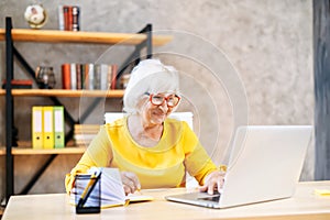 Senior woman is using laptop for work indoor