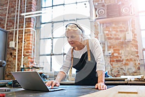 Senior woman using a laptop in a workshop