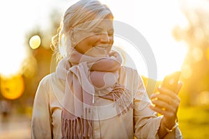 Senior woman using mobile phone outdoors in autumn