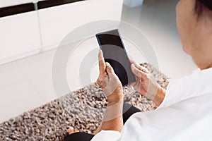 Senior woman using mobile phone while sitting on sofa at home