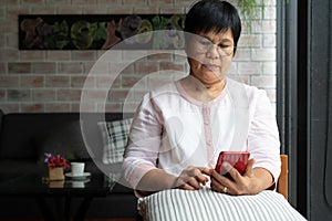 Senior woman using mobile phone while sitting on sofa at home