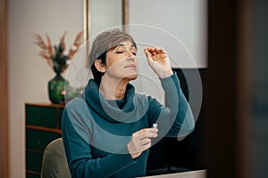 Senior woman using an nasal swab for covid 19 detection, self testing