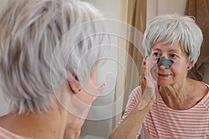 Senior woman using a nose strip to remove black dots