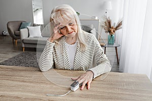 Senior woman using Oximeter at home. Healthcare Concept