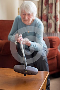 Senior Woman Using Reaching Arm To Pick Up Spectacles Case At Ho