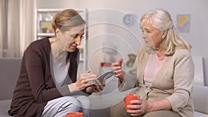 Senior woman using smartphone communicating with her mature neighbour, friends