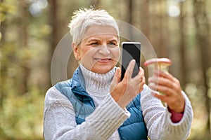 Senior woman using smartphone to identify mushroom