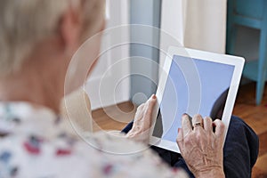 Senior woman using tablet computer, over shoulder view