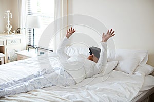 Senior woman using virtual headset on bed