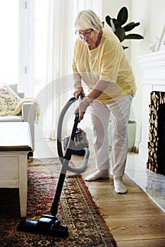 Senior woman vacuuming a carpet