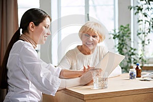 Senior woman visiting doctor, sitting at table in office, having appointment and consultation. Good result after