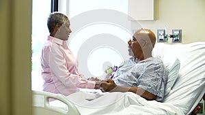 Senior Woman Visiting Husband In Hospital Room