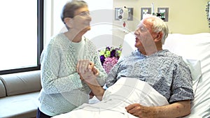 Senior Woman Visiting Husband In Hospital Room