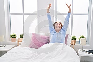 Senior woman waking up stretching arms at bedroom