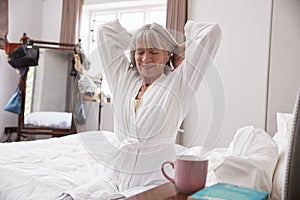 Senior Woman Waking Up And Stretching In Bedroom photo